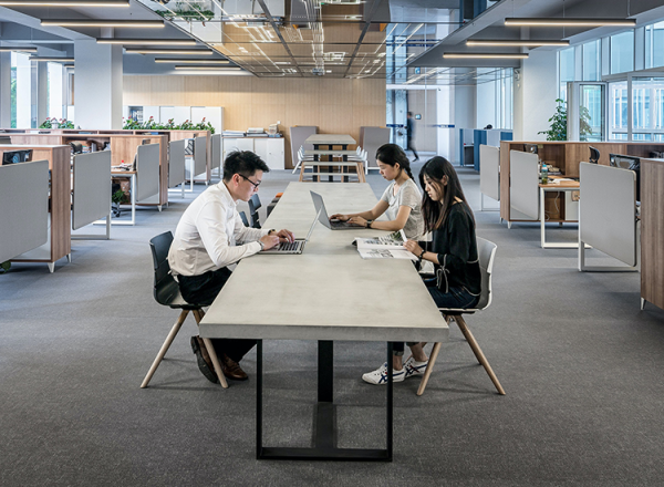 People on laptops at a desk in an office building