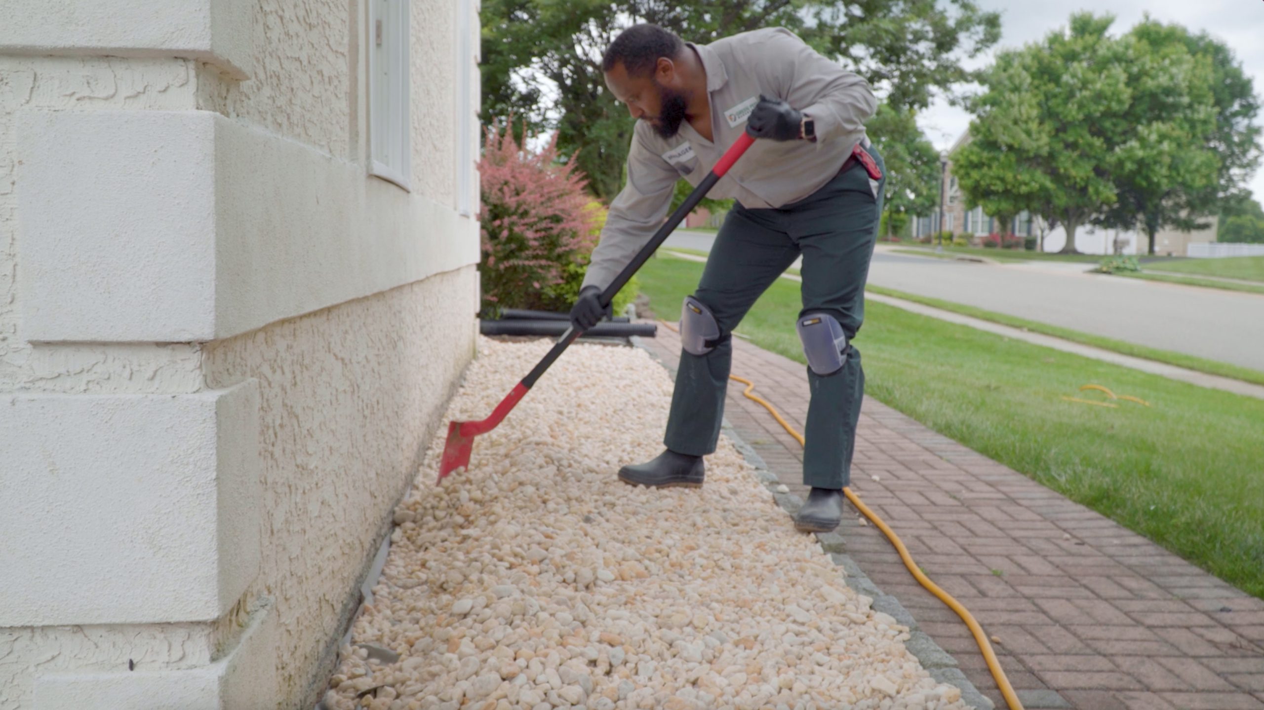 pest control technician clearing debris from around a home