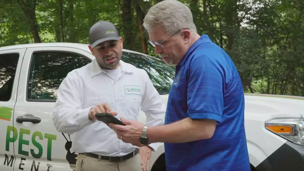Green_Pest_Management_technician_talking_with_customer Green Pest Management exterminator showing customer pest problems