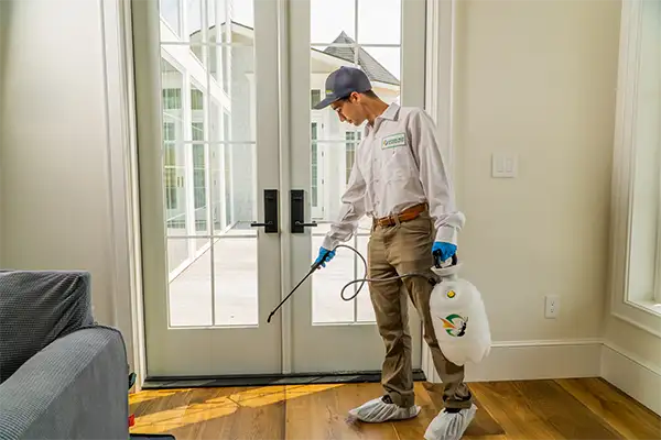 technician sprying inside home for cockroaches